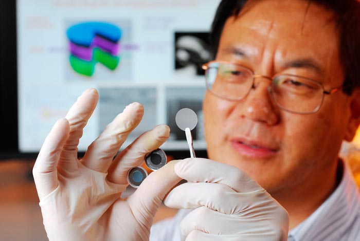 Zhong Lin Wang đang cầm các bộ phận của một tế bào năng lượng tự tích điện mới sử dụng chất liệu áp điện để biến đổi trực tiếp cơ năng thành hóa năng